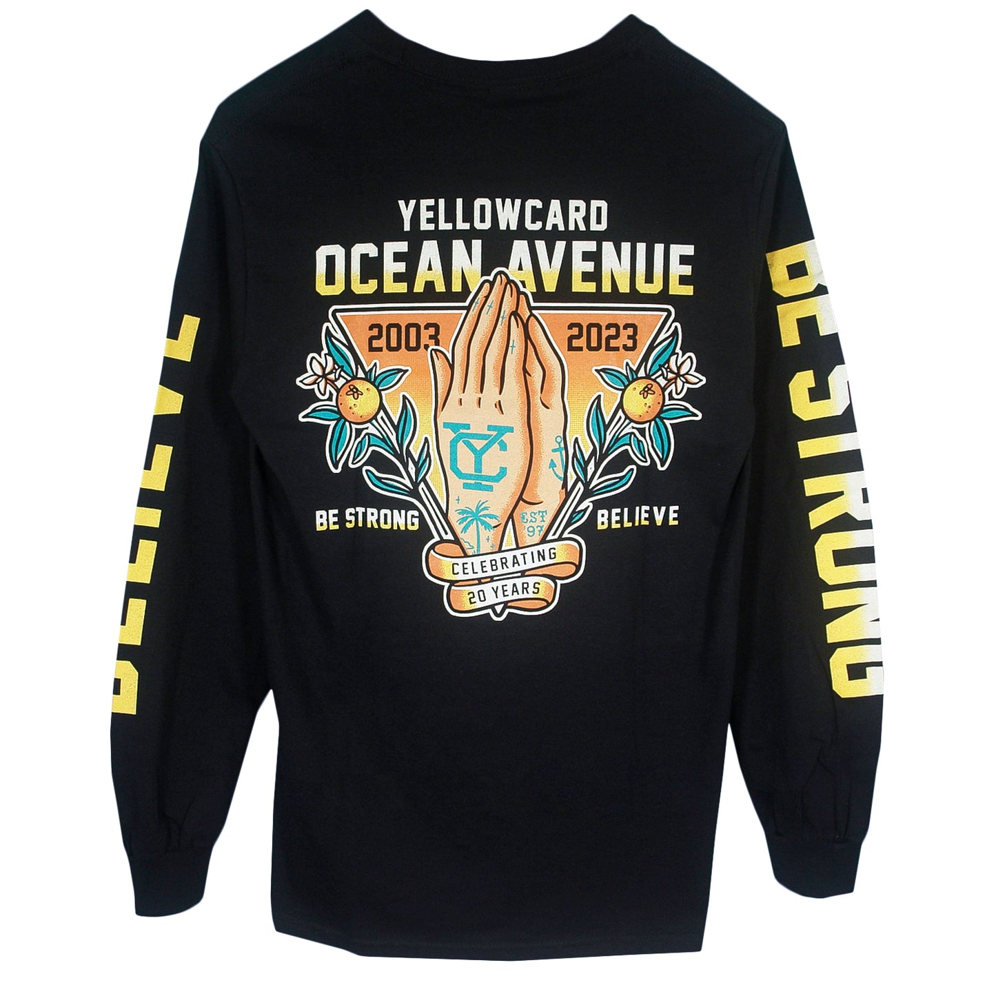 The Believe - Black Long Sleeve features a Yellowcard Ocean Avenue 2003-2023 and praying hands graphic on the back, with “Be Strong” and “Believe” text on the sleeves and bottom, celebrating 20 years.
