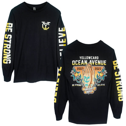 The Believe - Black Long Sleeve is printed on Gildan Ultra Cotton and features BE STRONG and BELIEVE on the sleeves, a yellow YC logo on the front, plus praying hands with YELLOWCARD OCEAN AVENUE 2003–2023 on the back.