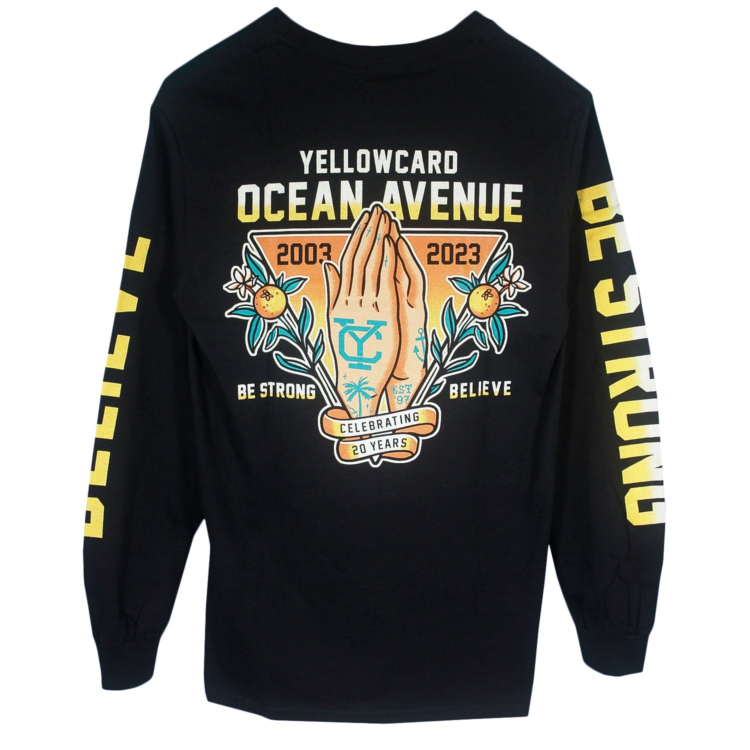 The Believe - Black Long Sleeve features a Yellowcard Ocean Avenue 2003-2023 and praying hands graphic on the back, with “Be Strong” and “Believe” text on the sleeves and bottom, celebrating 20 years.