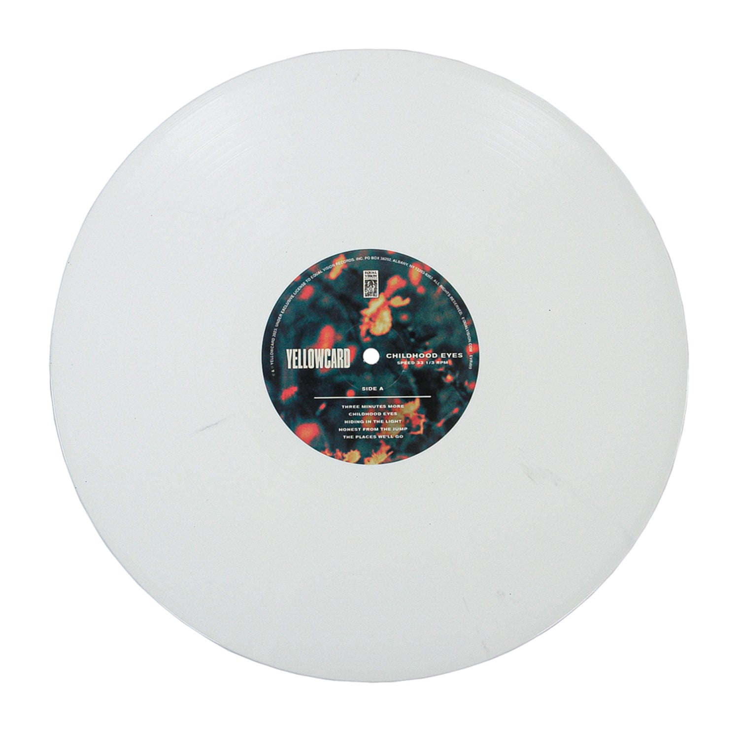 The Childhood Eyes - White - Vinyl LP features a white record with a black label displaying Yellowcard and song info, including "Childhood Eyes," set over a blurred background of orange and green lights.